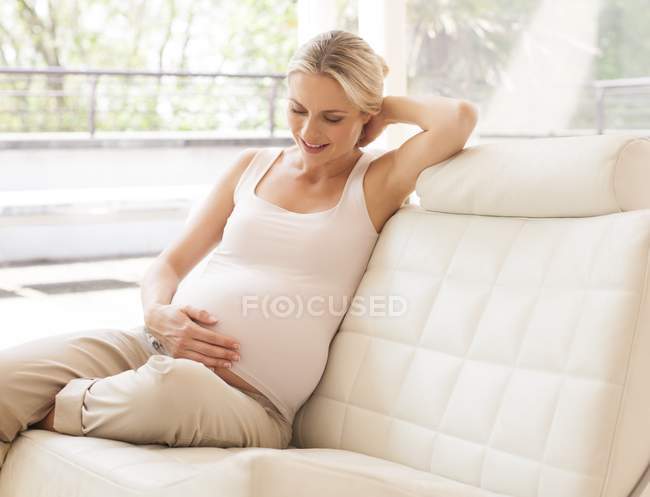 Pregnant woman holding hand to tummy — Stock Photo