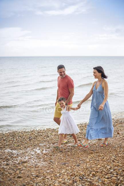 Genitori che camminano sulla spiaggia con figlia . — Foto stock