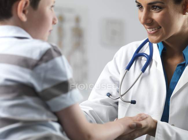Pediatra do sexo feminino conversando com menino da idade elementar . — Fotografia de Stock