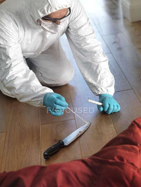 Científico forense en la escena del crimen recogiendo muestras de ADN de cuchillo como evidencia forense . - foto de stock