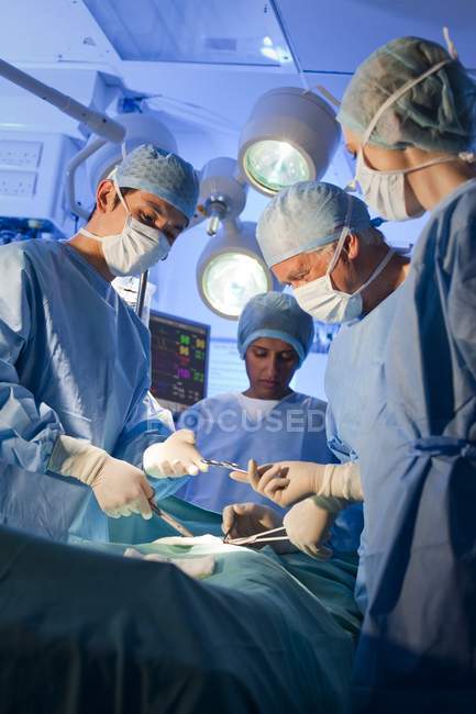 Squadra chirurgica in maschera che lavora in sala operatoria . — Foto stock