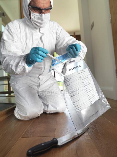 Cientista forense no local do crime recolhendo amostras de ADN da faca como prova forense . — Fotografia de Stock
