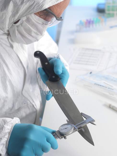 Científico forense midiendo hoja de cuchillo como evidencia forense . - foto de stock