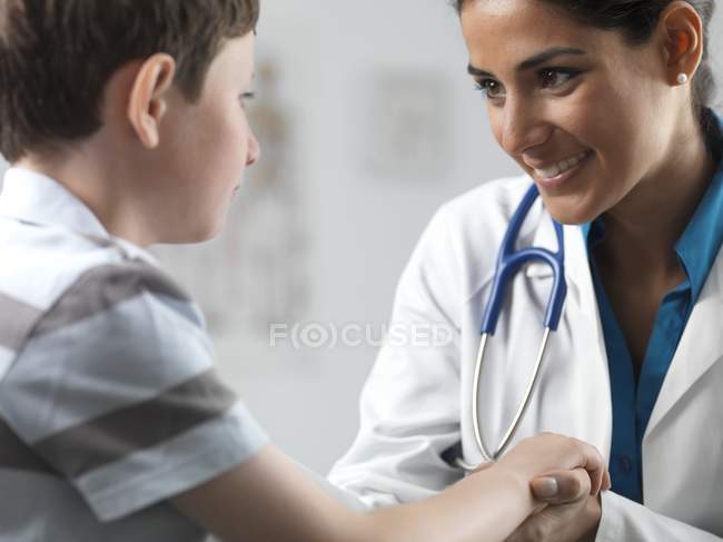 Female pediatrician talking to elementary age boy. — Stock Photo