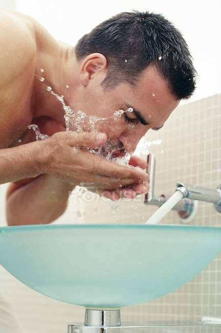 Mitte erwachsener Mann wäscht Gesicht im Badezimmer. — Stockfoto