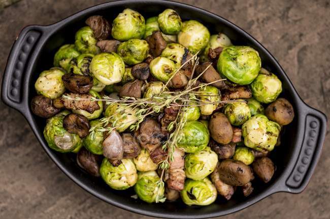 Brussels sprouts with mushrooms and pork in dish. — Stock Photo