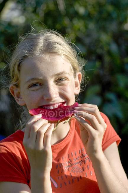Chica joven disfrutando de pitaya fruta y mirando en la cámara . - foto de stock