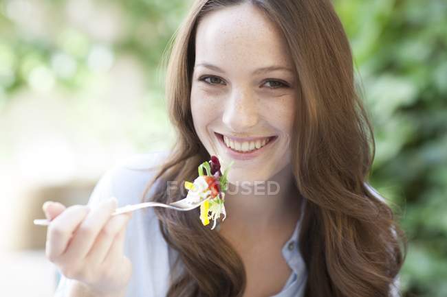 Молода жінка їсть салат з виделкою . — стокове фото
