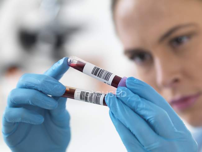 Женщина-ученый держит образцы крови в пробирках . — стоковое фото