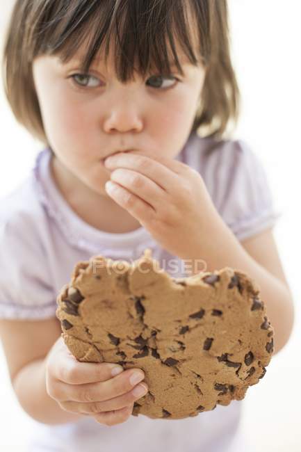 Toddler girl with bobbed hair eating chocolate cookie. — Stock Photo
