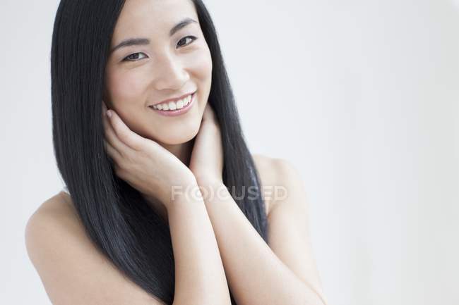 Portrait of Asian mid adult woman smiling with hands on chin. — Stock Photo