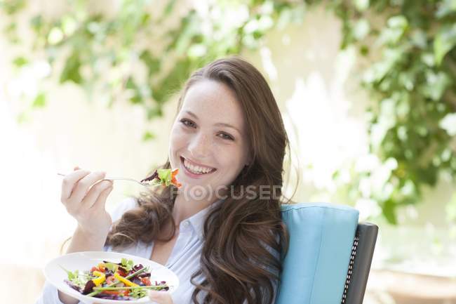 Mujer joven comiendo ensalada de verduras con tenedor . - foto de stock