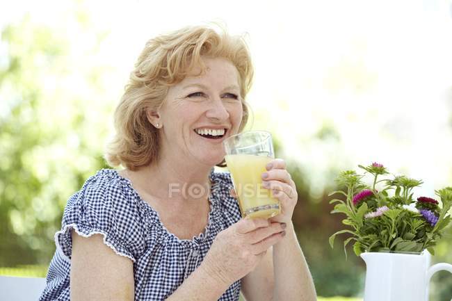 Reife Frau trinkt Fruchtsaft. — Stockfoto