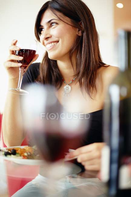 Mujer adulta media bebiendo vino mientras cena en el restaurante . - foto de stock