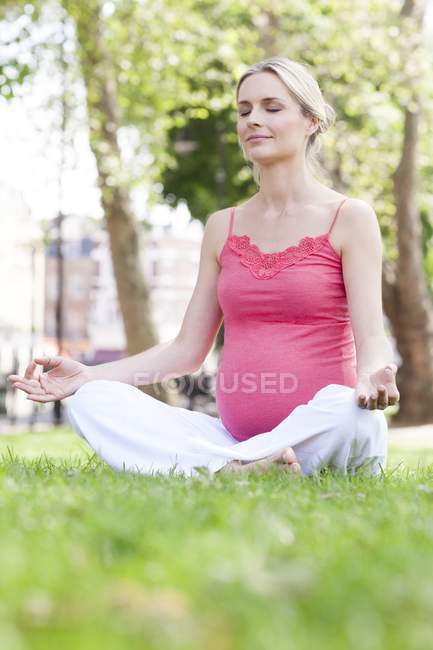 Pregnant woman meditating outdoors — Stock Photo