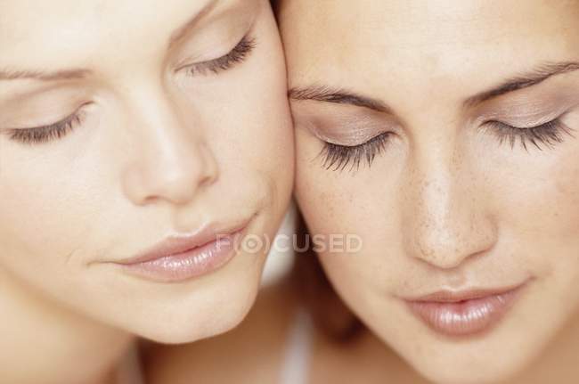 Retrato de cerca de dos mujeres jóvenes con los ojos cerrados . - foto de stock