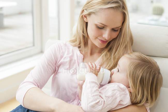 Mother feeding toddler daughter with bottle of milk. — Stock Photo