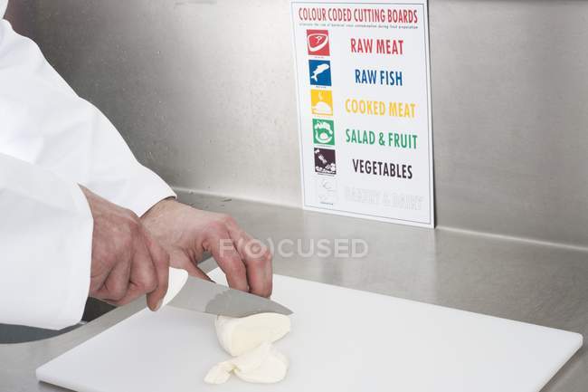 Vista ritagliata dello chef che taglia il formaggio in cucina . — Foto stock