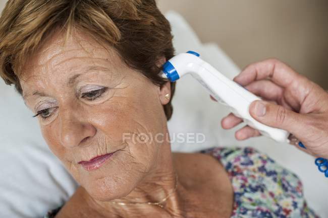 Infirmière prenant à la main la température du patient avec thermomètre numérique . — Photo de stock