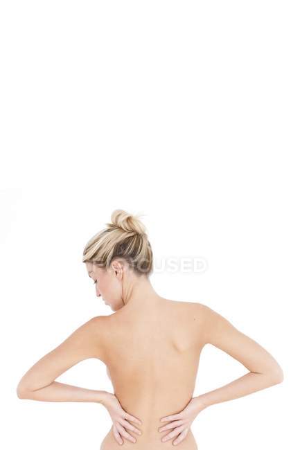 Vista trasera de mujer rubia con las manos en las caderas sobre fondo blanco - foto de stock