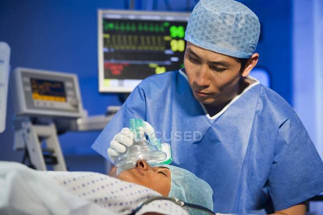 Cirurgião asiático ajustando anestésico para paciente do sexo feminino — Fotografia de Stock