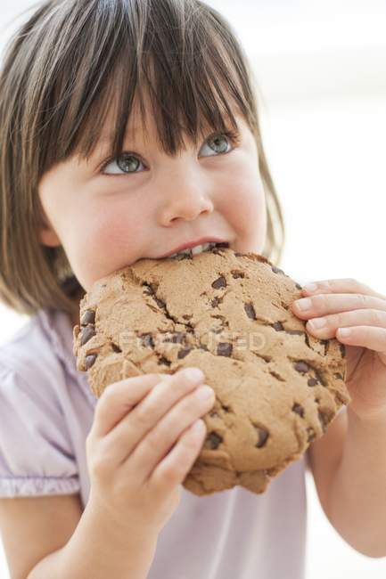 Kleinkind Mädchen mit wippenden Haaren isst Schokoladenkeks. — Stockfoto