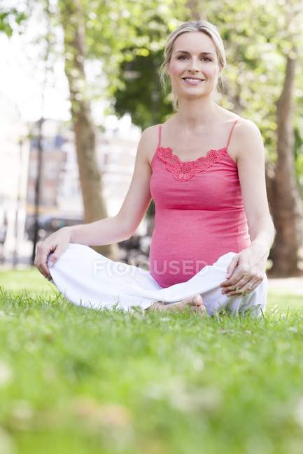Вагітна жінка сидить на траві — стокове фото