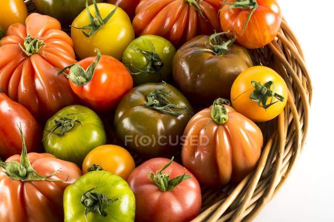 Heritage tomatoes in basket on white. — Stock Photo