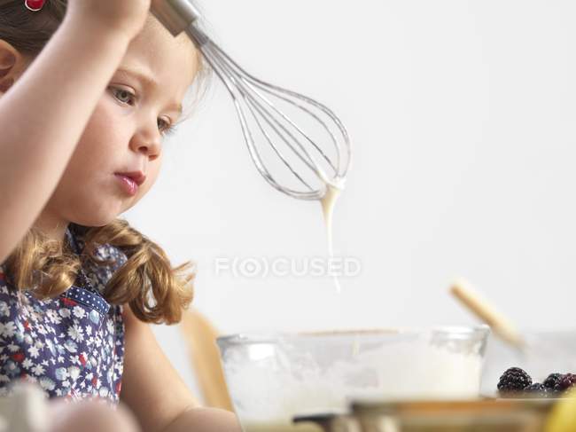 Menina pré-escolar com batedor de balão na cozinha . — Fotografia de Stock