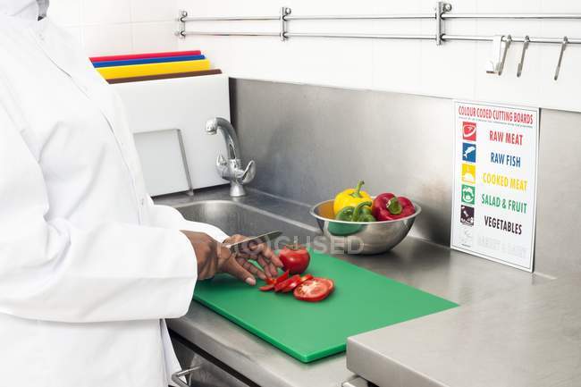 Vista recortada del chef cortando tomates en la cocina . - foto de stock