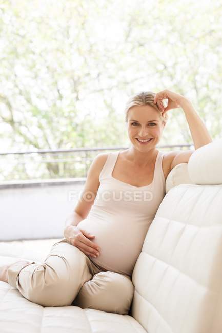 Donna incinta seduta sul divano — Foto stock
