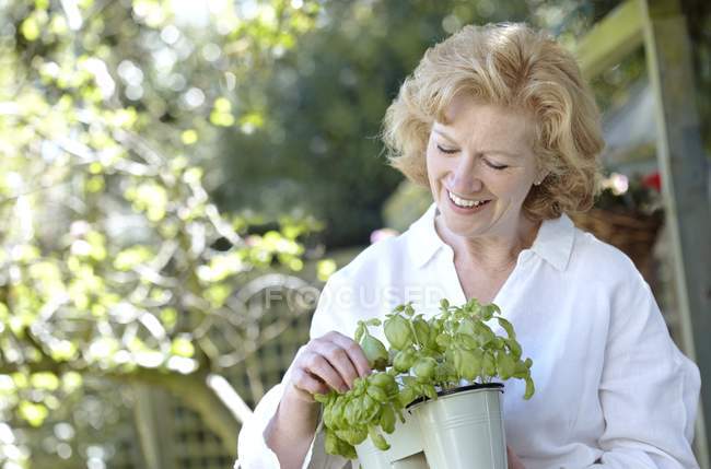 Reife Frau hält Topfpflanze im Garten. — Stockfoto