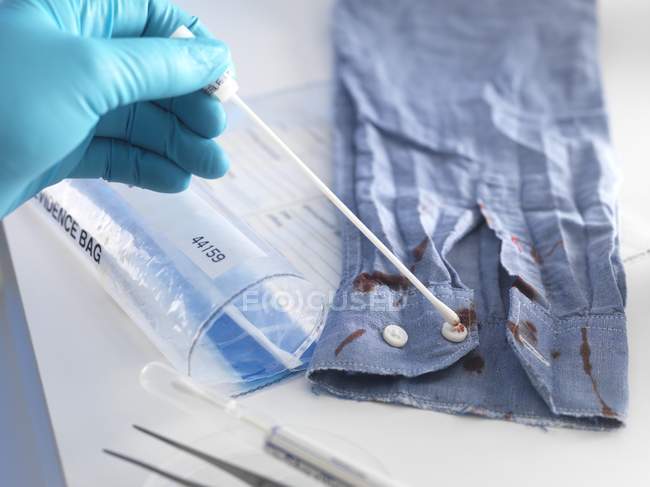 Gerichtsmediziner nimmt Abstrich von blutverschmiertem Hemd als Beweismittel. — Stockfoto