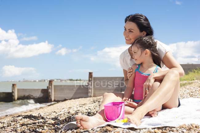 Мати і дочка сидять на пляжі і дивляться на погляд . — стокове фото