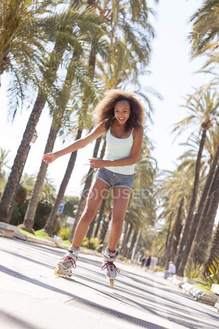 Mixed race teenage girl rollerblading in street. — Stock Photo