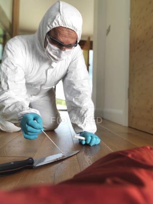 Científico forense en la escena del crimen recogiendo muestras de ADN de cuchillo como evidencia forense . - foto de stock