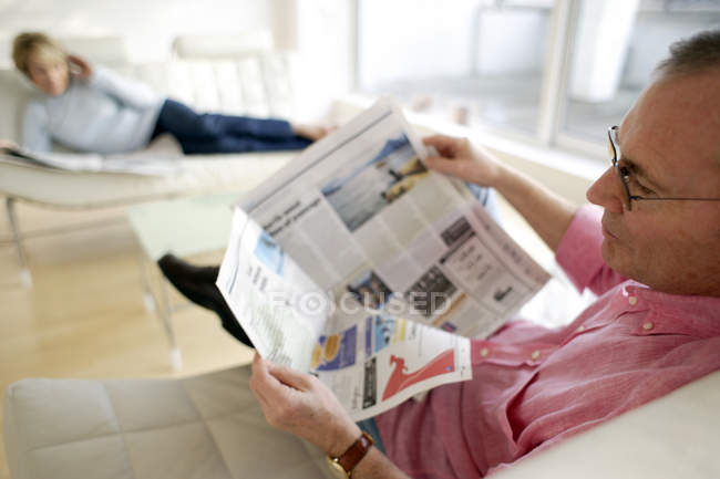 Чоловік читає газету, розслабляючись вдома — стокове фото