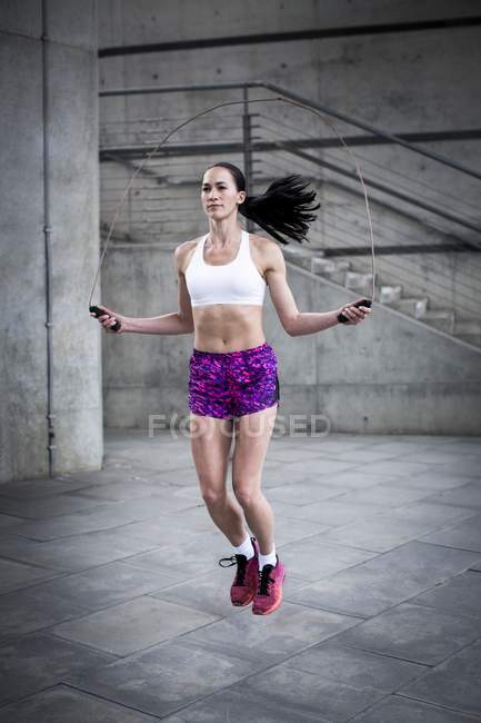 Jeune femme sauter avec la corde — Photo de stock