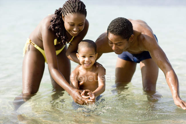 Família com filho pré-escolar brincando na água do mar . — Fotografia de Stock