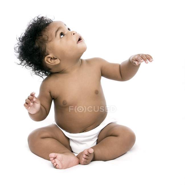 Menina do bebê sentado e olhando para cima no fundo branco . — Fotografia de Stock