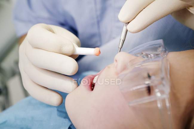 Dentista realizando tratamento odontológico na menina . — Fotografia de Stock