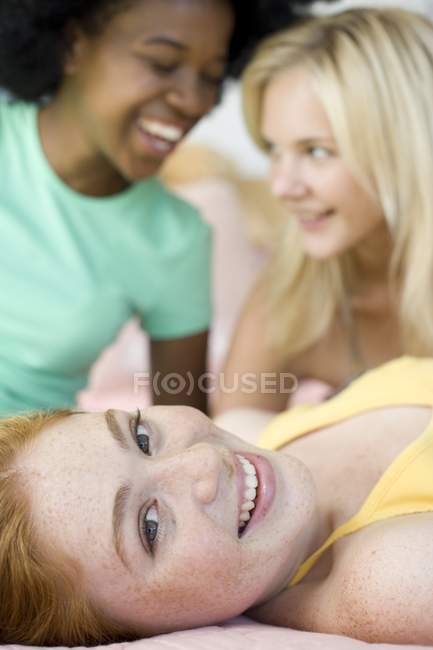Drei fröhliche Teenager-Mädchen lachen, während sie drinnen herumhängen. — Stockfoto