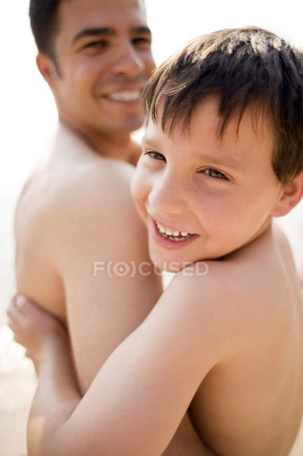 Pai e filho abraçando na praia . — Fotografia de Stock