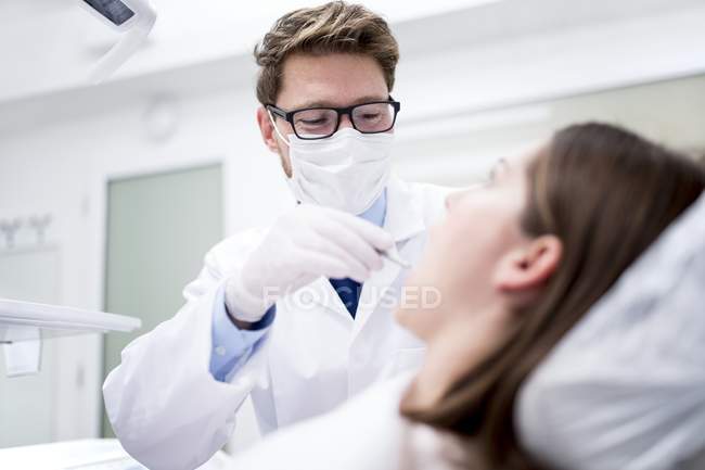 Dentista examinando os dentes dos pacientes na clínica odontológica . — Fotografia de Stock