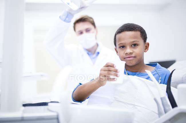 Portrait of boy holding cup of water in clinic. — Stock Photo