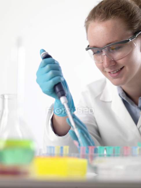 Cientista feminina pipetando líquido em tubos Eppendorf . — Fotografia de Stock