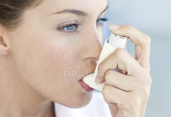 Retrato de mujer joven usando inhalador de asma . - foto de stock
