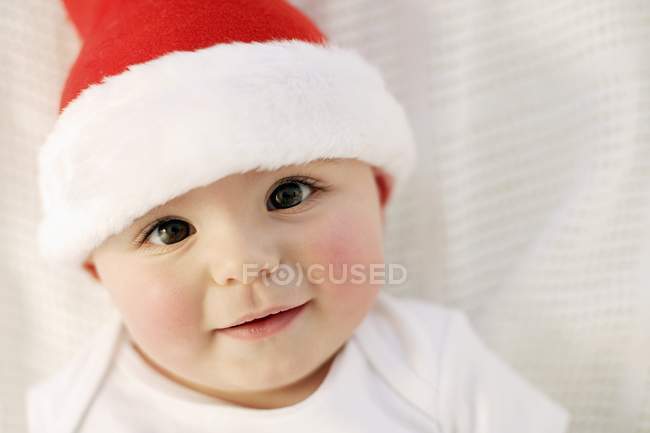 Дитячий хлопчик в капелюсі Санта посміхається і дивиться в камеру . — стокове фото