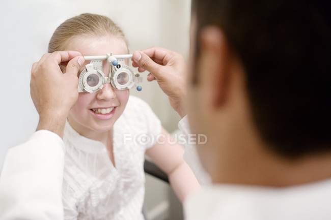 Оптик подстраивает рамки для осмотра глаз девочки-подростка . — стоковое фото