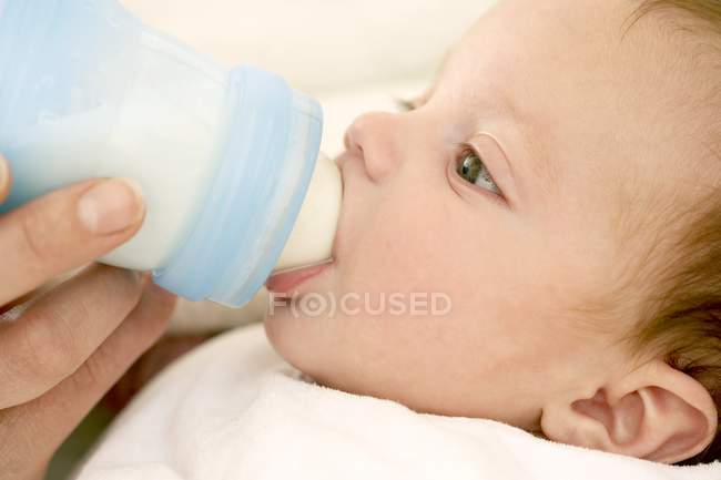 Mutter füttert Baby-Tochter mit Milch aus Flasche. — Stockfoto